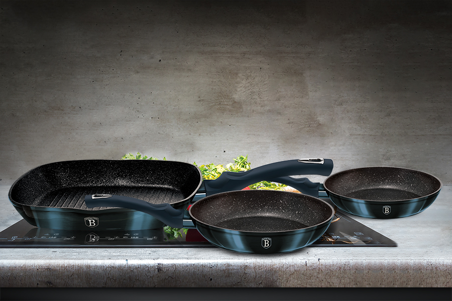 Green enamel stewpot with parsley and two tomatoes on black indu